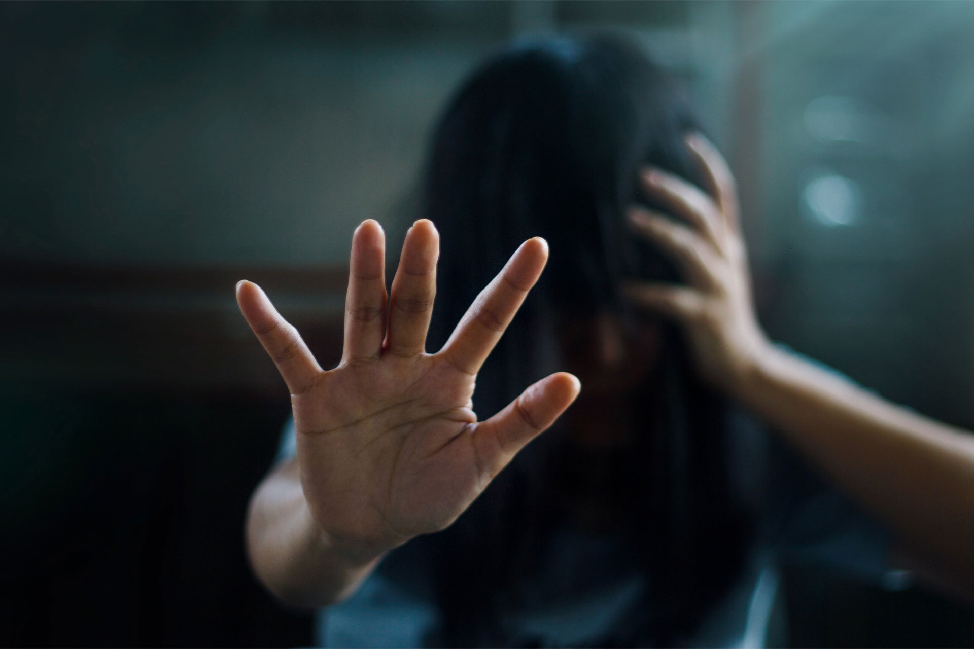 A woman shows her hand as if to say stop in a dark environment